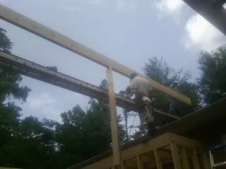 Carpenter setting a ridge beam over a new addition frame — Ice Dam Removal by Roofing Brothers in Ozone Park