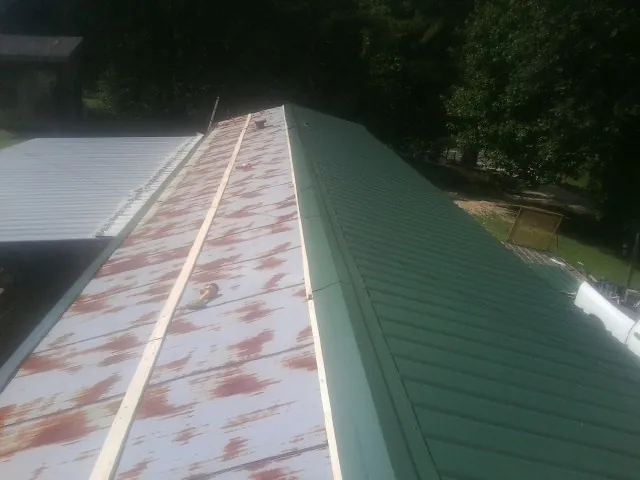 Old rusted panels beside newly installed green metal roofing — Wind Damage Roof Repair by Roofing Brothers in Ozone Park