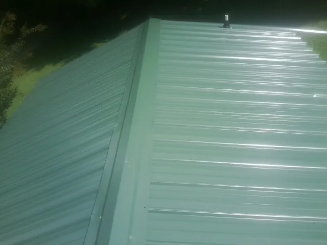 New green metal panels meeting at the ridge of a roof — Flat Roof Repair work by our crew in Ozone Park