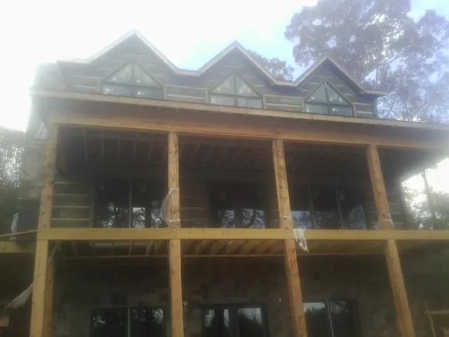 Dormers and porch framing on a large log home under construction — Roof Coating work by our crew in Ozone Park