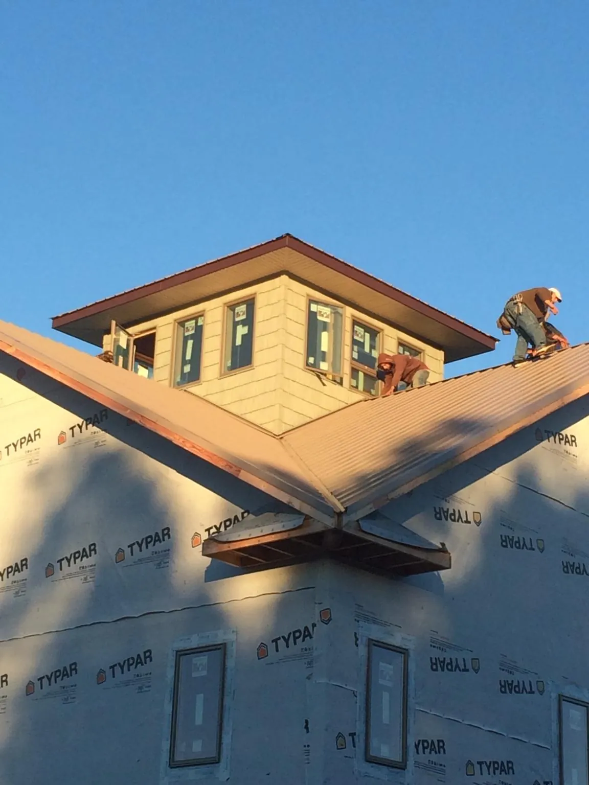 Roofers working around a rooftop cupola on a new metal roof at sunset — Roof Waterproofing in Ozone Park by Roofing Brothers
